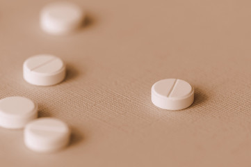 White tablets scattered on a surface close up. Brown color toned