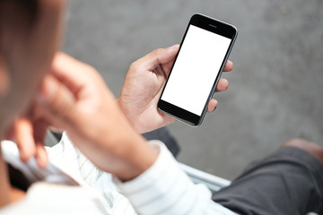 Cropped shot view of man hands holding smart phone with blank copy space screen for your text message or information content, female reading text message on cell telephone during in urban setting.