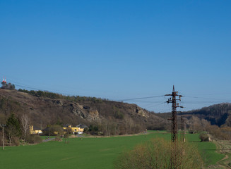 Fototapeta na wymiar Green meadow and rocks in city Beroun, early spring, blue sky. Czech Republic