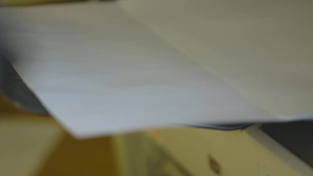 Handheld, interior, extreme close up shot of a printer printing out paper.