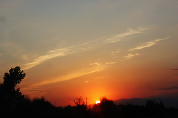 Amazing sunset sunrise with sun over mountain