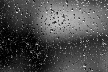 Raindrops on glass in rainy weather close up. Natural background black and white