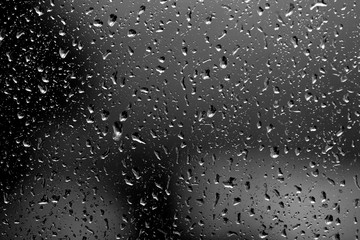 Raindrops on glass in rainy weather close up. Natural background black and white
