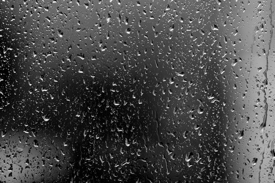 Raindrops On Glass In Rainy Weather Close Up. Natural Background Black And White