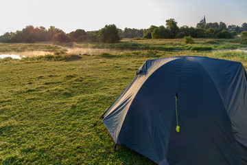 Tourist tent in the meadow by the river