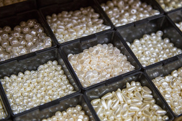 pearl beads in different boxes. Material for handmade jewelery. Background for the store and the master. Shop for creativity. Fashionable craft of women.