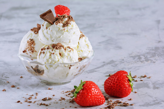 Vanilla ice cream decorated with chocolate chips and strawberries. Delicious refreshing dessert. Photo with copy space.