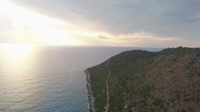 Albanian Riviera at sunset with the sun rays piercing through the clouds to light up the Adriatic Sea. The coastline with huge cliff and the ocean crashing in