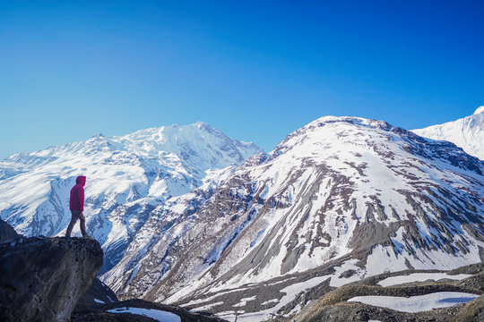 Explorer concept: Man wearing red jacket standing on the edge of a clift in Tilicho Base Camp located in Annapurna Circuit