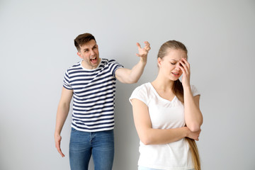 Young quarrelling couple on light background