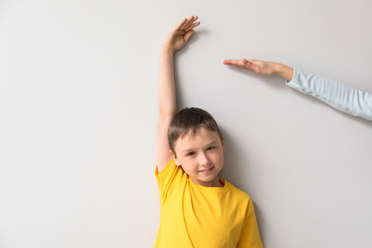 Mother measuring height of her son near wall