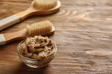 Brushes and body scrub on wooden background