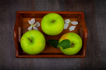 Green apples on a wooden tray.