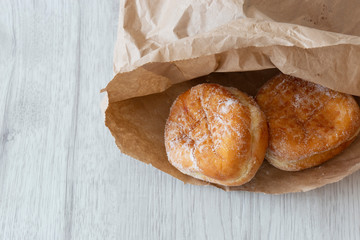 Jam doughnuts in a brown paper bag,  recycling packaging,  on a grey wood background