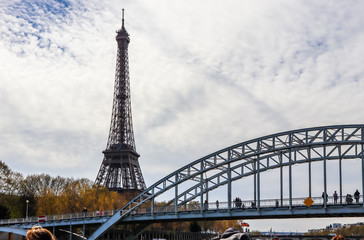 Eiffel Tower against blue sky with clouds and pedestrian bridge Passerelle Debilly over Seine River. Paris France. April 2019