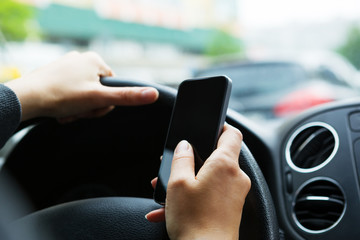 Woman sitting in the car and messaging on mobile phone.