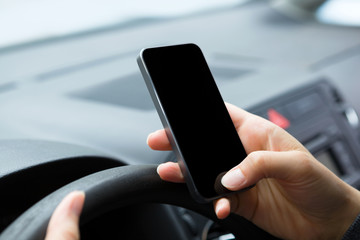 Woman sitting in the car and messaging on mobile phone.