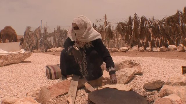 Traditionally dressed woman bakes homemade bread in Bedouin camp