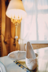 Beautiful white bridal shoes standing on the table in the room