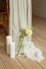 Branch of blooming white peony tulip Mattiola branch in a glass vase white wax candles stand on the wooden light floor indoors