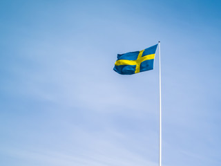 Swedish flag against blue sky. Swedish flag fluttering on wind. Sveriges nationaldag. National Day of Sweden. Swedish Flag Day.
