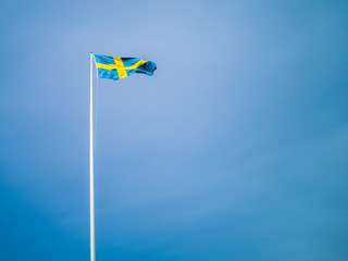 Swedish flag against blue sky. Swedish flag fluttering on wind. Sveriges nationaldag. National Day...