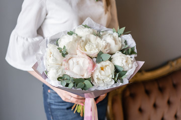 White peonies with eucalyptus in womans hand. Beautiful peony flower for catalog or online store. Beautiful bouquet. Floral shop concept . Fresh cut Flowers delivery