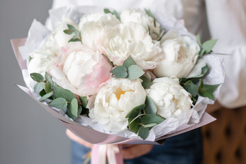 White peonies with eucalyptus in womans hand. Beautiful peony flower for catalog or online store. Beautiful bouquet. Floral shop concept . Fresh cut Flowers delivery