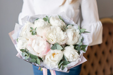 White peonies with eucalyptus in womans hand. Beautiful peony flower for catalog or online store. Beautiful bouquet. Floral shop concept . Fresh cut Flowers delivery
