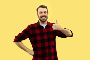 Half-length close up portrait of young man in shirt on yellow background. The human emotions,...