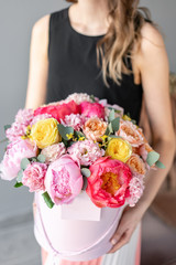 coral and pink peony. Beautiful bouquets of mixed flowers in womans hands. Packed in a round box of hat. Floral shop concept . Fresh cut Flowers delivery