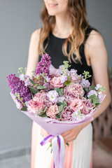 Flower shop. Beautiful bouquet of mixed flowers in woman hand. the work of the florist at a flower shop. Delicate Pastel color. Fresh cut flower. Pink and lilac color