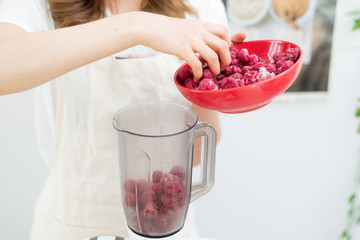 Raspberry Smoothies A woman puts fresh-frozen raspberry berries in a shaker. The concept of healthy eating.