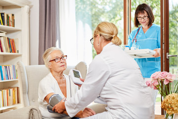 Ärztin misst den Blutdruck bei einer Seniorin