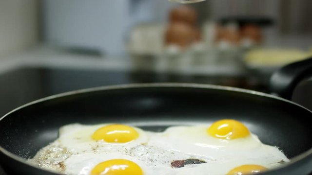 mother breaks an egg for scrambled eggs and use papper pot