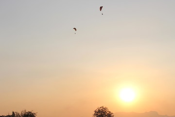 The sun is below the horizon. Travelers are driving Paramotor.