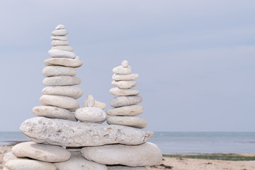Fototapeta na wymiar triple balance tower white grey pebble on a beach