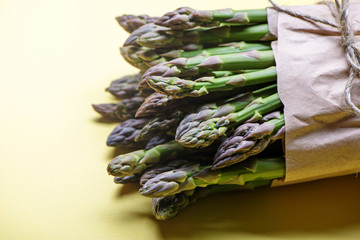 Bunch of fresh green asparagus on yellow background. Top view.