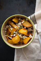 Plate of hot Patatas Bravas, a traditional Spanish tapas dish, fried or oven baked potato cubes until crispy served with parsley, spicy aioli garlic mayonnaise sauce and feta cheese crumbs