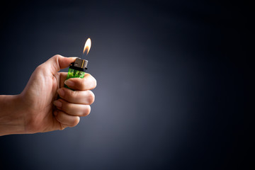 Close up woman hand holding a burning lighter in the dark background.