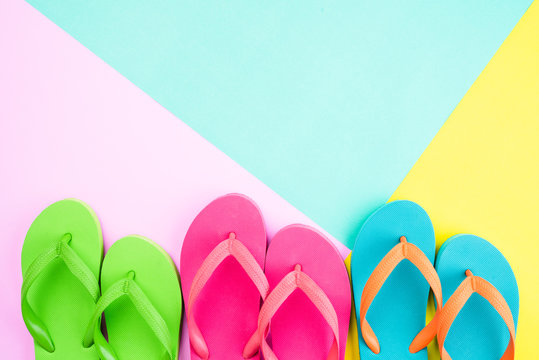 Top view of colorful flip flop on pink and yellow background for summer holiday and vacation concept.