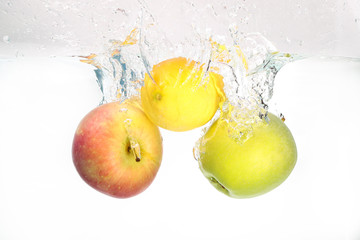 Fototapeta na wymiar Two apples and lemon splash in water on white