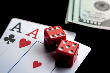 Close-up - Two aces, playing cards and red gaming dices on black table.