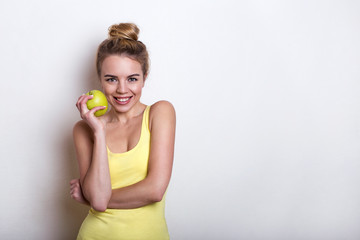 Beautiful young woman with apple on a light background