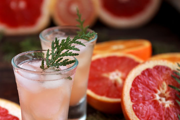 Drink glass with alcoholic cocktail with grapefruit and citrus, ice and juice on a wooden board, old rustic style
