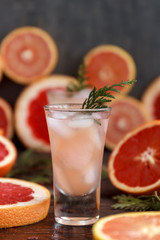Fresh alcoholic cocktail with grapefruit and citrus, ice and juice, drink glass on a wooden board, selective focus