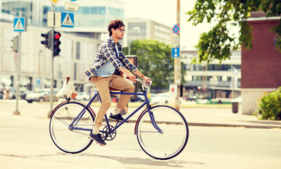 Fototapeta premium people, style, leisure and lifestyle - young hipster man with shoulder bag riding fixed gear bike on city street