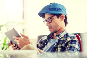 leisure, technology, communication and people concept - creative man with tablet pc computer sitting at cafe table