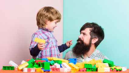 little boy with bearded man dad playing together. happy family. leisure time. building home with colorful constructor. child development. father and son play game. colorful life. make colorful mood
