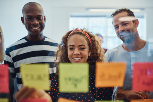 Smiling designers brainstorming together with sticky notes in an
